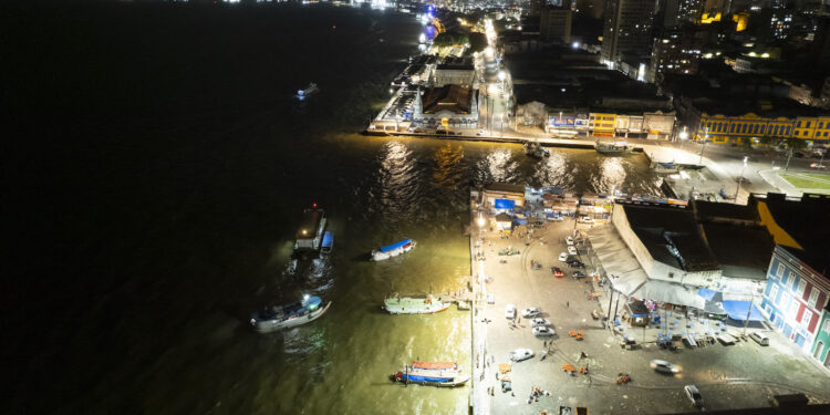 An aerial of a fishing town with lights and boats on the water at night