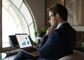 Businessman looking at graphs on a laptop screen, apparently lost in thought