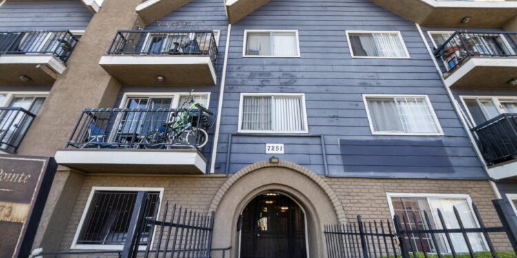 An arched entry corridor leads into a multi-story apartment building.