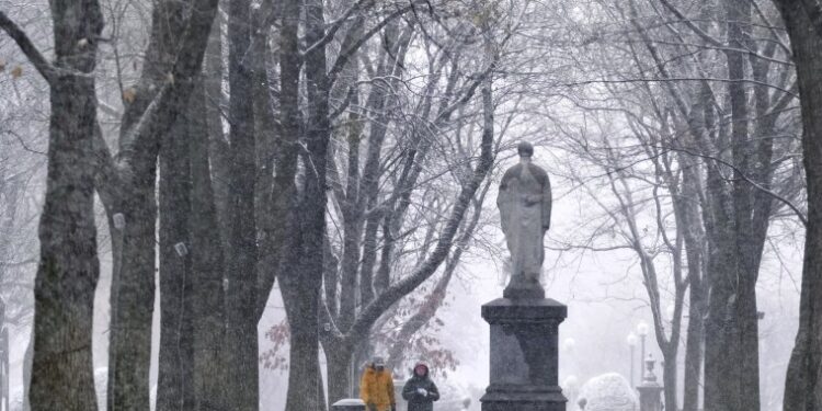 Image: Snow falls as a couple walks along the Commonwealth Avenue Mall in the Back Bay neighborhood of Boston on Dec. 20, 2024.