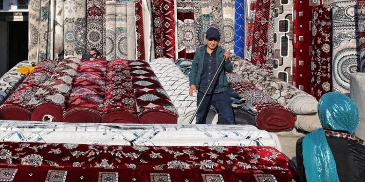 © Reuters. A vendor sells carpets at a local market in the settlement of Hulbuk, formerly known as Vose, in the Khatlon region, Tajikistan, December 12, 2024. REUTERS/Stringer