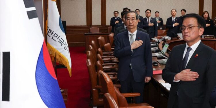 © Reuters. Acting South Korean President and Prime Minister Han Duck-soo salutes to a national flag during a cabinet meeting at the government complex in Seoul, South Korea, December 14, 2024.   Yonhap via REUTERS