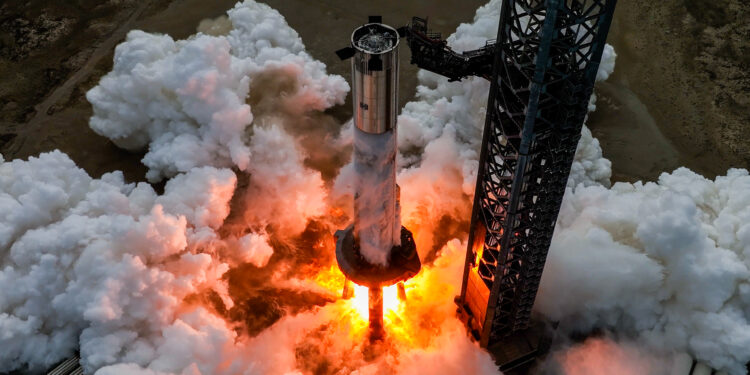 A giant Starship rocket booster firing its engines on the launch pad.