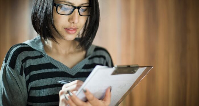 An investor takes notes on a clipboard.