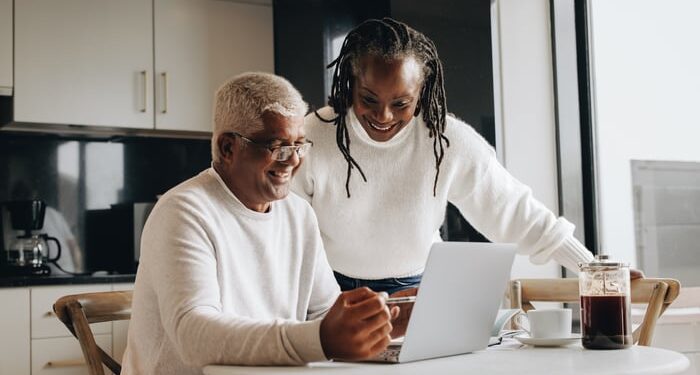 Smiling couple looking at laptop together in kitchen.