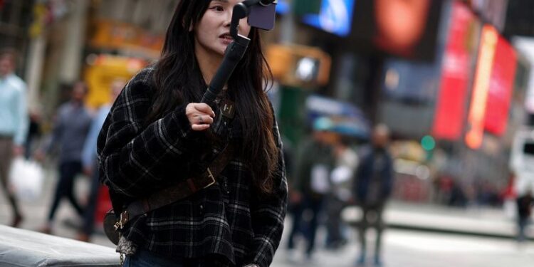 © Reuters. A woman makes a video with a mobile phone to post on TikTok as she stands in Times Square in New York City, New York, U.S., March 13, 2024. REUTERS/Mike Segar/File Photo