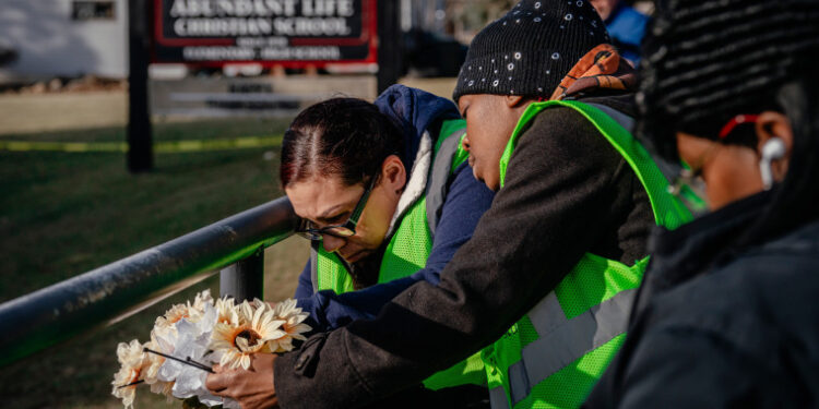 People bring flowers to a makeshift memorial at Abundant Life Christian School